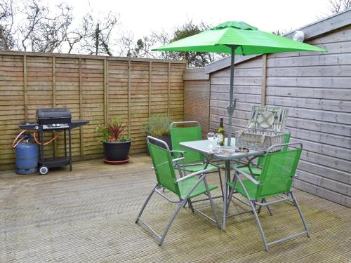 a table and chairs with a green umbrella on a patio at Tresidder Barn in Constantine