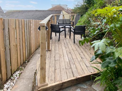 a wooden deck with chairs and a table on it at The Dawn in Looe