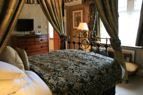 a bedroom with a canopy bed and a dresser at The Old Registry guest house in Haworth