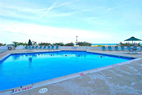 a large blue swimming pool with chairs and an umbrella at Pyramid 8K in Ocean City