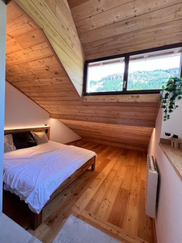 an attic bedroom with a bed and a window at Appartement moderne style chalet in Le Monêtier-les-Bains