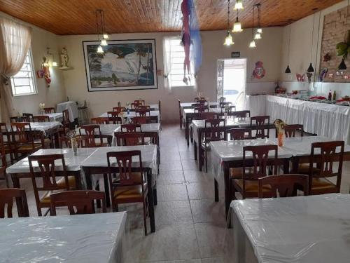 a dining room filled with tables and chairs with white tables at Pousada Vila Bela in Poços de Caldas