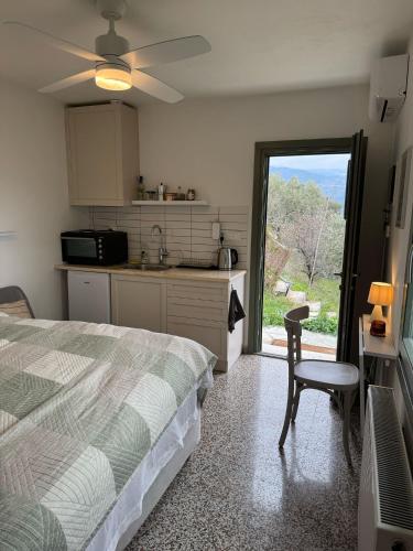 a bedroom with a bed and a kitchen with a window at Admonis - Home in the olive grove in Melissátika