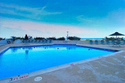 a large blue swimming pool with chairs and an umbrella at Pyramid 6G in Ocean City