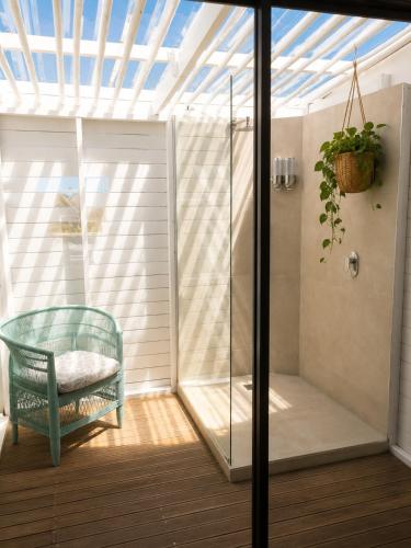 a conservatory with a glass shower and a chair at CANAL GUEST HOUSE - Waterfront Boutique B&B in St Francis Bay