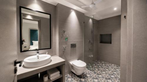 a bathroom with a sink and a toilet and a mirror at The Bay Suites - MMR in New Town