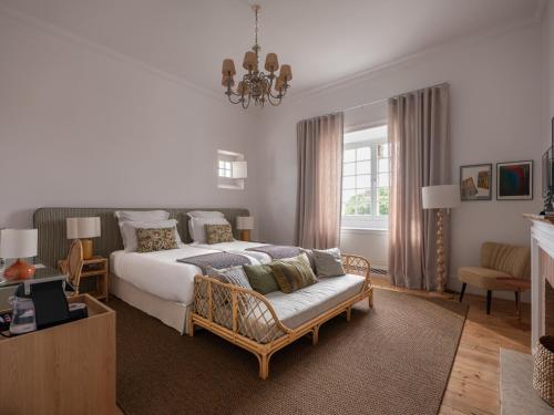 a bedroom with a bed and a couch and a chandelier at Villa Vasco da Gama in Cascais
