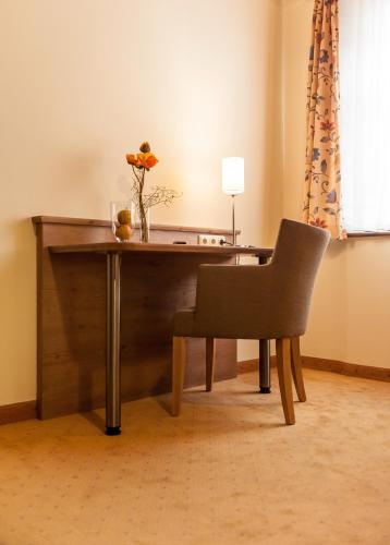 a wooden desk with a chair and a vase of flowers at Löwen Hotel & Restaurant in Marktbreit