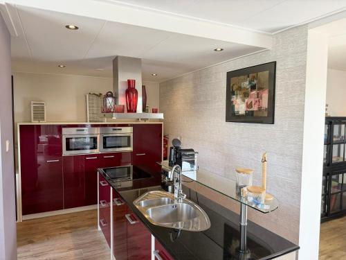 a kitchen with red cabinets and a sink at Texelheerlijk 4 in De Koog