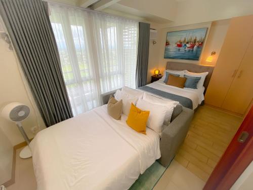 two beds in a hotel room with yellow pillows at Paladium Iloilo Smart Home Condo in Iloilo City