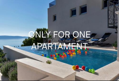 a swimming pool with balls in the water next to a building at Luxury Apartments Podgora in Podgora