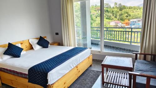 a bedroom with a bed and a large window at Ganga Nature Nest in Hawālbāgh