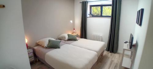 two beds in a small room with a window at L'Etable d'Armand in Névez