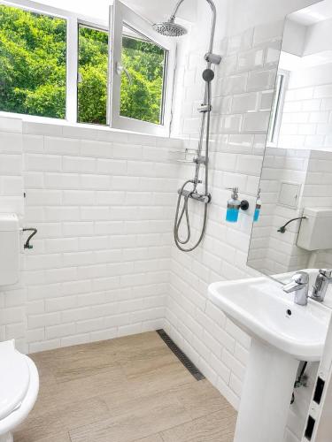 a white bathroom with a shower and a sink at Terasa Baniei in Bucovăţ