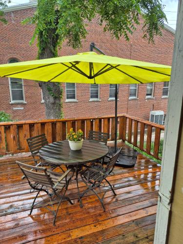 a table and chairs with a yellow umbrella on a deck at The John Sydney House in Hannibal