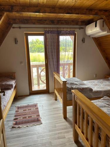 a bedroom with two beds and a large window at Vikendica Vesic Tegare in Bratunac