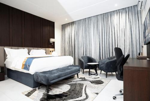 a hotel room with a bed and a desk and chairs at Oxvera Hotel Limited in Umuahia