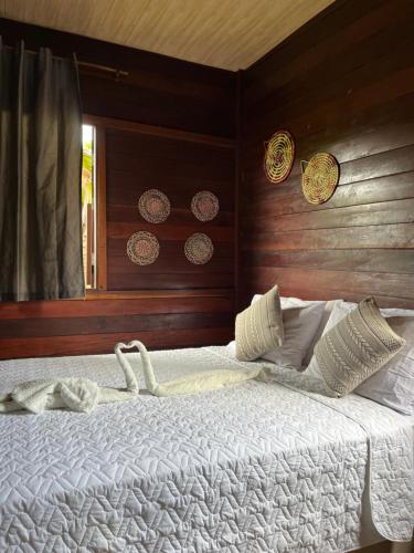 a bed with white sheets and pillows in a bedroom at Chalés Paradise in Atins