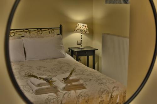 a mirror reflecting a bedroom with a bed with white sheets at Gartagani Guest House in Stemnitsa