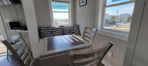 a dining room table and chairs in a room with two windows at Oceanfront Townhouse steps to the Beach in Atlantic Beach