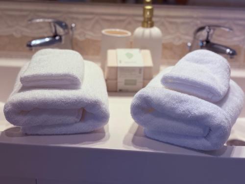 a pile of towels sitting on top of a sink at ViLLA HELENA - anciennement LE CLOS D'IGNAC in Lège-Cap-Ferret
