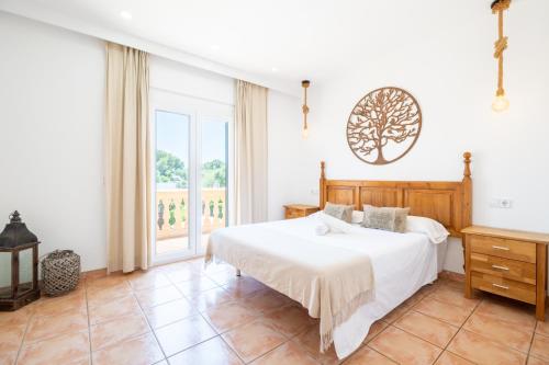 a bedroom with a white bed and a window at Villas2meet La Siesta in Cala Romàntica