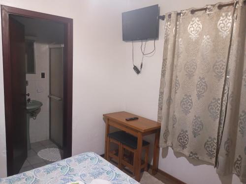 a bedroom with a bed and a table and a television at Marins Pousada - Campos do Jordão in Campos do Jordão