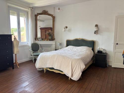 a bedroom with a bed and a mirror and a chair at La briqueterie in Bourseville