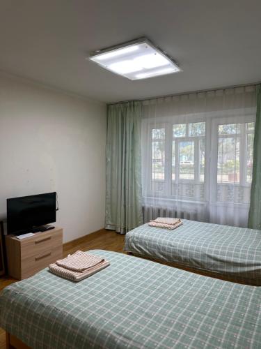 a bedroom with two beds and a flat screen tv at Cozy 2 BR Apartment with Easy Access in Ulaanbaatar