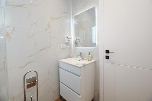 a white bathroom with a sink and a mirror at LiEl Holiday in Vlorë