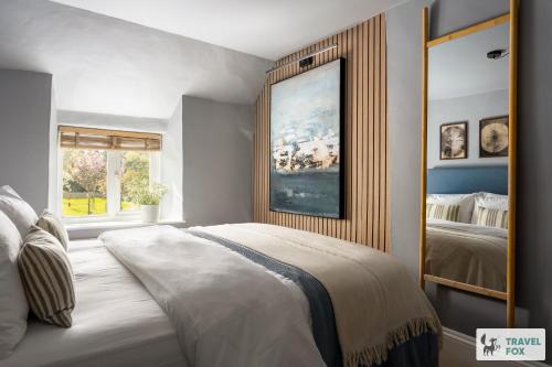 a bedroom with a large bed and a painting on the wall at Charlotte's Cottage, a Charming Cotswolds Getaway in Adlestrop