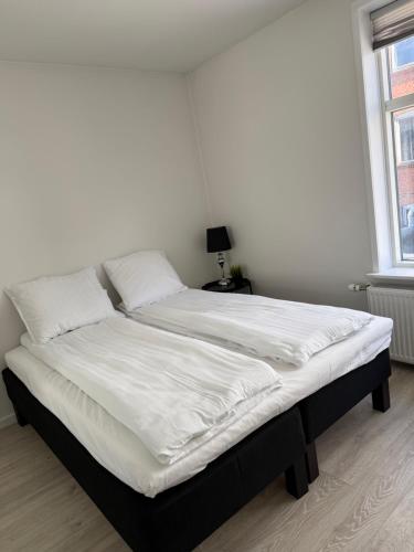 a bed with white sheets and pillows in a bedroom at Lille Vedelsborg 1 in Vejle