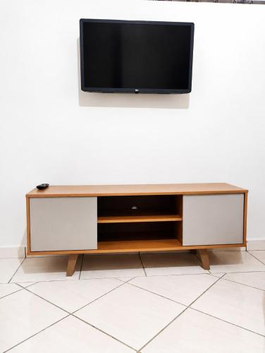 a flat screen tv on top of a wooden entertainment center at Studio aconchegante com ar-condicionado e Smart TV in Bauru