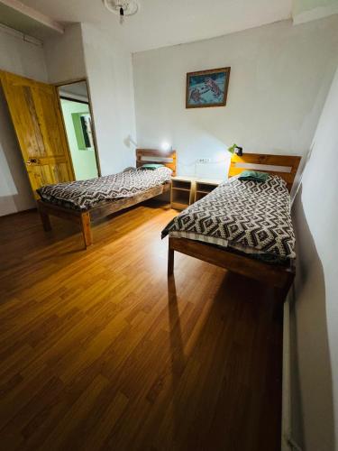 a room with two beds and a wooden floor at Kurjun in Karakol