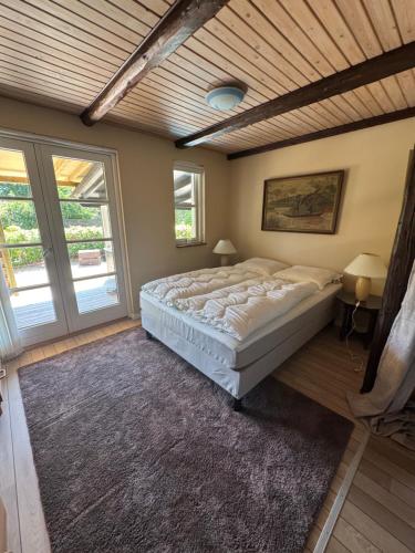 a bedroom with a large bed in a room with windows at Bøtøstrand anneks in Bøtø By