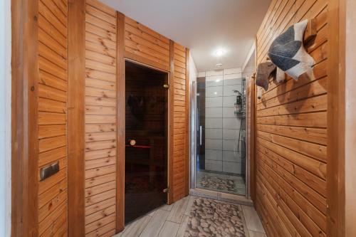 a bathroom with wooden walls and a walk in shower at Zaļais Stūrītis - Semi-Detached Holiday Home with Private entrance & Indoor Sauna in Liepāja