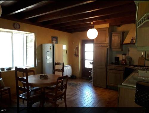 a kitchen with a table and chairs and a refrigerator at La maison de la Mouline in Arette