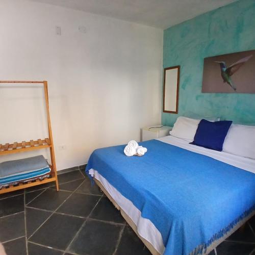 a bedroom with a blue bed and a mirror at Villa dos Pássaros Paraty Hospedagem in Paraty