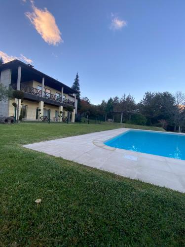 a house with a swimming pool in front of a building at Gerês Pichoses Camping - Quartos in Geres