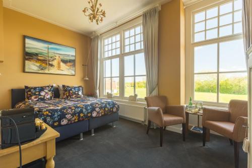 a bedroom with a bed and a table and windows at Pastorie Stella Marie in Oudeschild