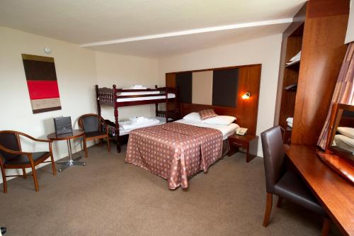 a hotel room with a bed and a desk and a bedroom at Normandy Hotel (Near Glasgow Airport) in Paisley