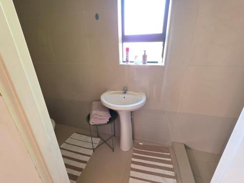 a small bathroom with a sink and a window at Mutare Fairbridge Executive Suites in Umtali