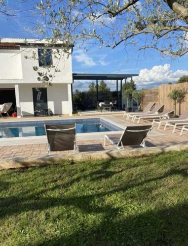 a swimming pool with lounge chairs and a house at Villa Klara in Gedići