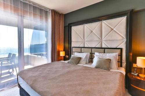 a bedroom with a large bed with a large window at Azure Coast Deluxe Residence - Budva Seafront Living Suites in Bečići