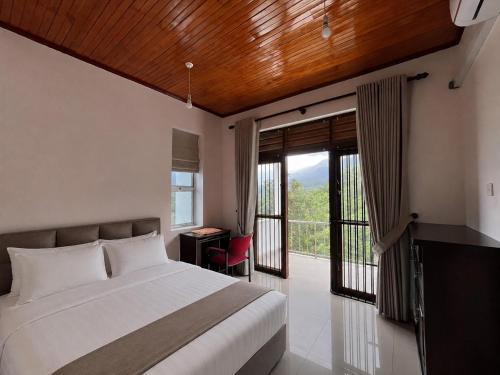 a bedroom with a bed and a desk and a balcony at Oli Villa in Belihuloya