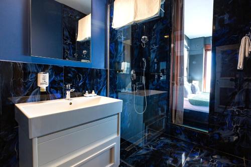 a blue bathroom with a sink and a shower at Azure Coast Deluxe Residence - Budva Seafront Living Suites in Bečići