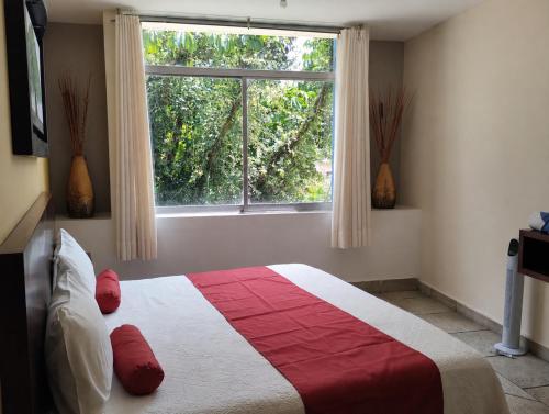 a bedroom with a red and white bed and a window at Hotel Tepoztlán in Tepoztlán