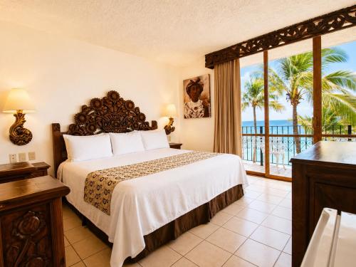 ein Schlafzimmer mit einem Bett und Meerblick in der Unterkunft Playa Los Arcos Hotel Beach Resort & Spa in Puerto Vallarta