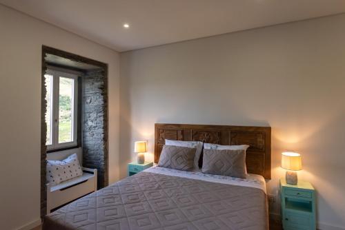 a bedroom with a bed with two night stands and a window at Feel Discovery Casa Fonte do Lagar in Desejosa
