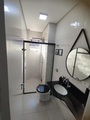 a bathroom with a toilet and a sink and a mirror at Sobrado Matinhos 480 m da praia l novo l central 3quartos in Matinhos